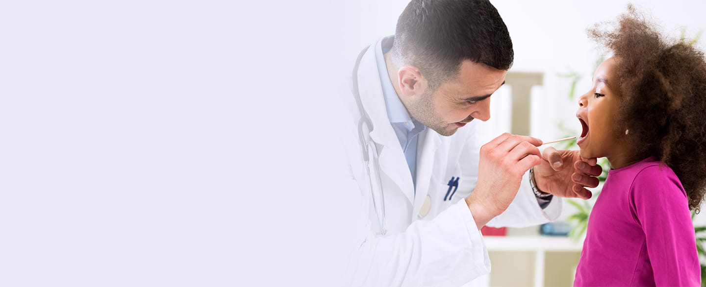 Doctor looking in young girls mouth.